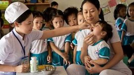 Health workers administer vitamins to children