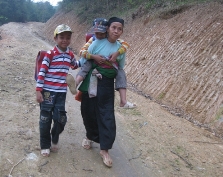 A grandmother carries her grandchild 6 km to school