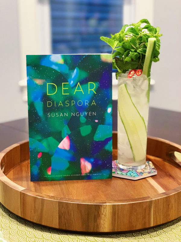 The book Dear Diaspora by Susan Nguyen and a cocktail drink